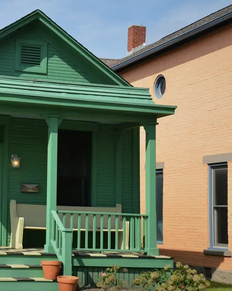 Green cottage with a covered front porch