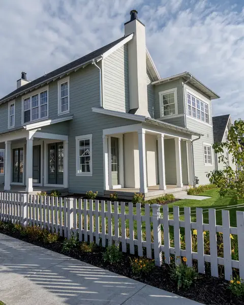 White farmhouse-style home behind a picket fence