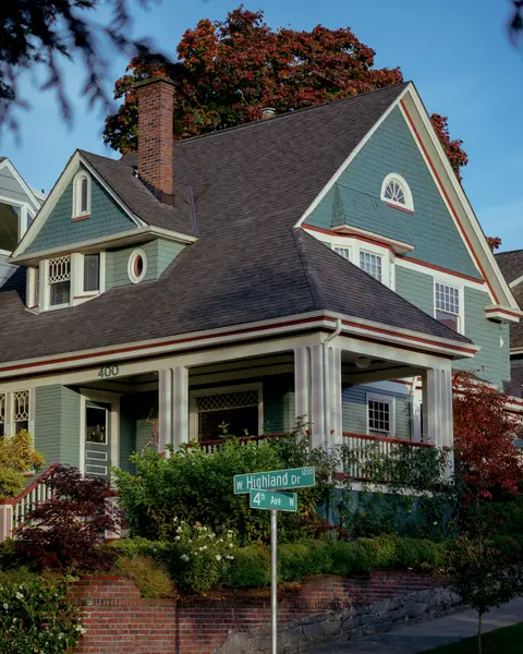 Blue craftsman with a front gable and porch behind a garden