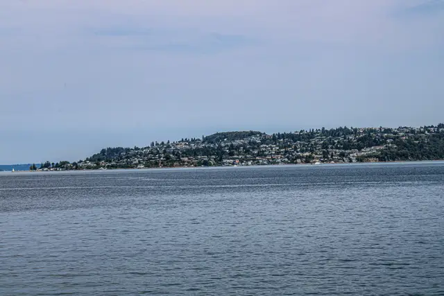 Wide view across Puget Sound water to a wooded island shoreline